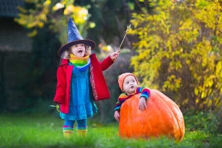 A witch girl and a pumpkin boy playing in the park