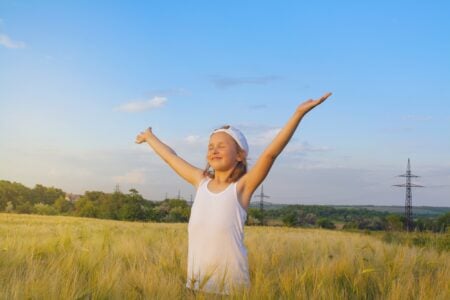 Lucky girl raising her hands happily in the meadow