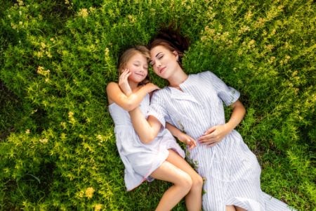 Mother and daughter laying on the grass on a sunny day