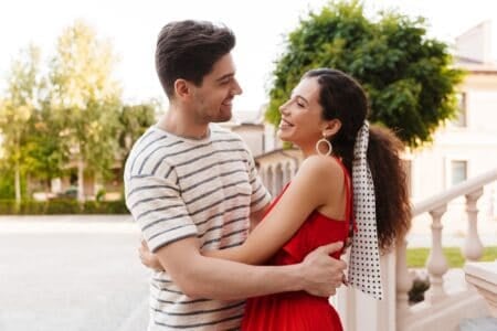 Cheerful couple looking at each other and hugging while standing outdoors