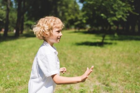 Curly-haired blonde boy playing in the park