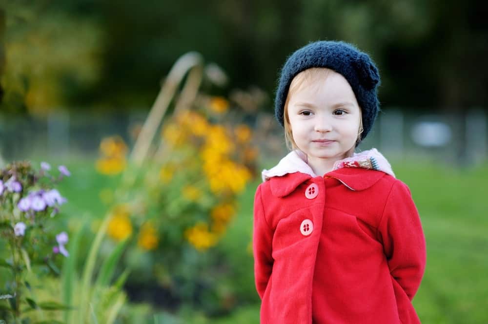 Cute little girl wearing beanie in autumn park