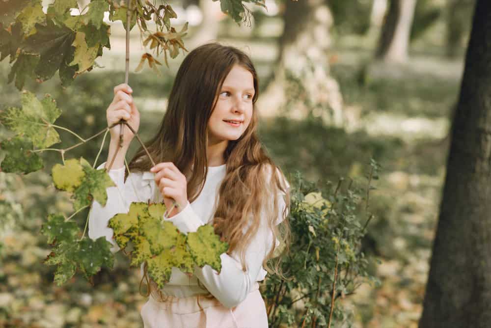 Cute little girl in a white dress playing in the park