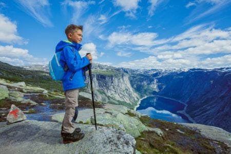 Cute Norwegian boy hiking in the mountains