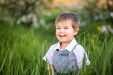 Happy little boy in denim overalls playing in the park