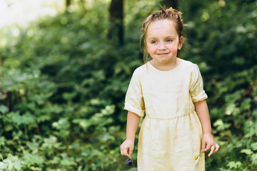 Cute little girl in yellow sundown across the forest