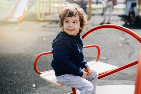 Young boy siting on a swing at the park