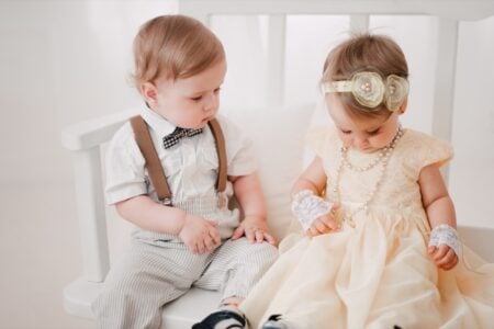 Two adorable babies sitting on a bench.