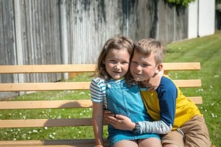 Two happy kids sitting on the bench together