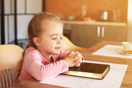 Little girl with the Bible praying at home