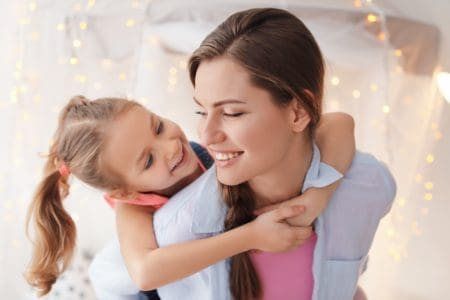 A cute little girl hugging her mother at home