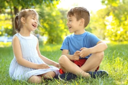 Little girl and boy sitting on the grass in the park