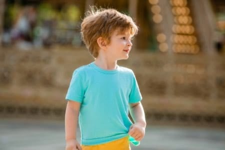 Happy little boy walks in summer amusement park