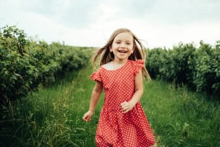 Beautiful young girl in red ploka dress having fun in the field