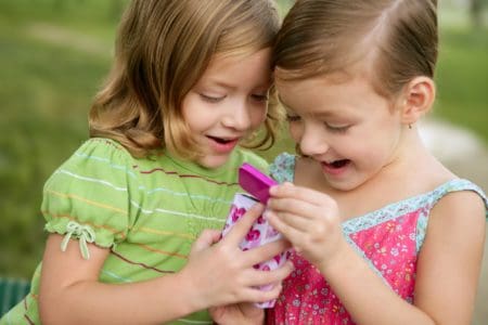 Two twin girls opening a pink box with presents