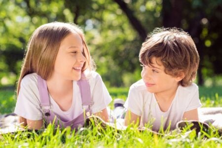 A girl and a boy lying on the grass in the park.