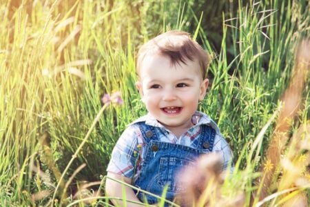 Happy little boy sitting on the grass