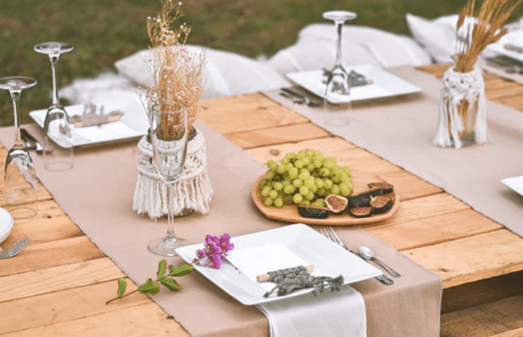 Green grapes on white ceramic plate beside stainless steel fork and knife on brown wooden table