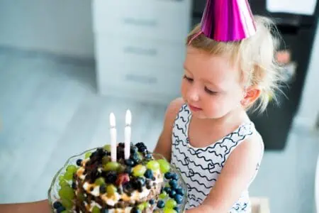 Little girl looking at the second birthday cake.