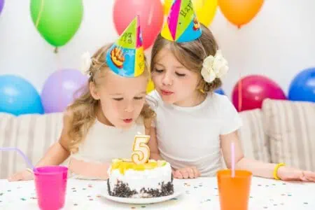 Two little girls looking at the fifth birthday cake.