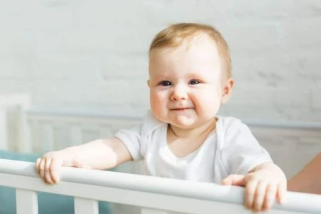 Baby standing inside a crib