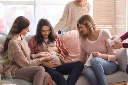 A pregnant woman receiving gifts from her friends at a baby shower.