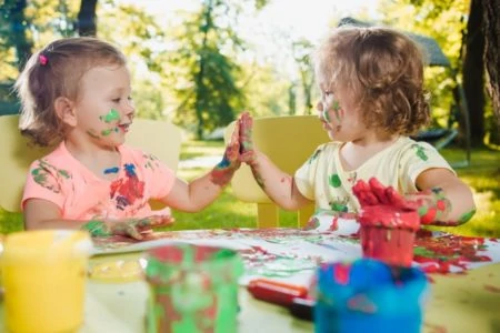 Two little girl painting messily outdoors