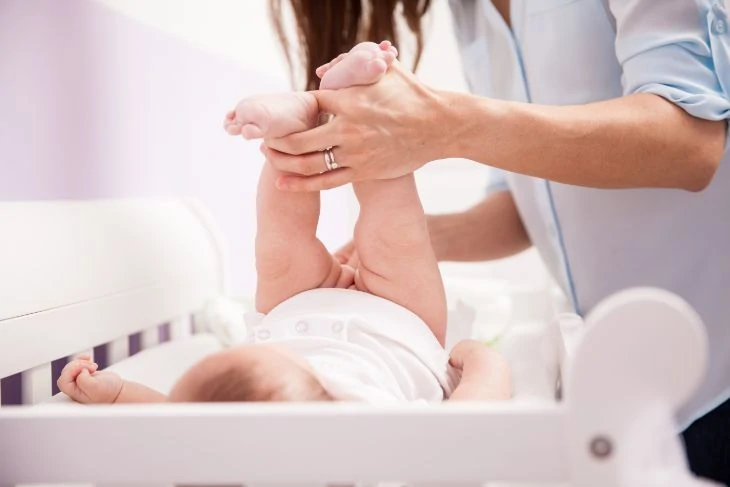 Mother cleaning baby's bottom with a baby wipe