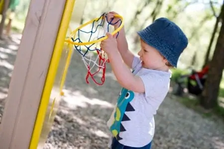 Toddler playing with basketball hoop