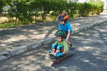 Young boy pushing his little brother on a skateboard