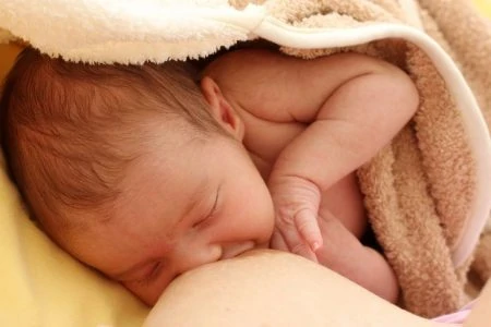 Mother breastfeeding her baby underneath a cover