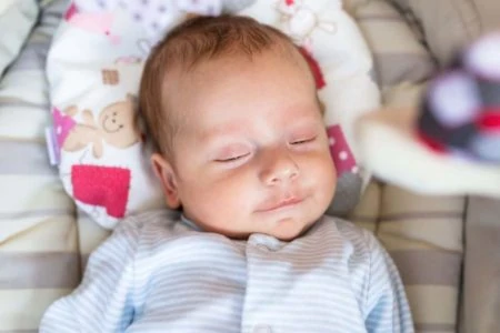 Adorable infant sleeping quietly on a head shaping pillow