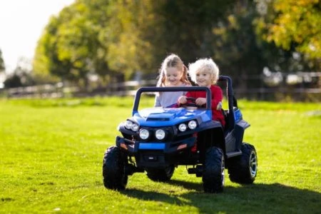 Little girl and boy riding an electric car in the park