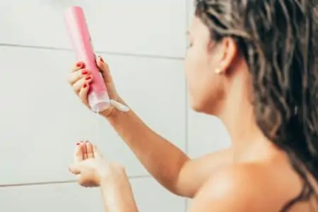 Young woman washing hair with shampoo in the shower