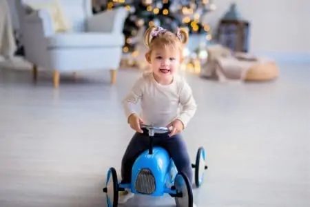 Cute little girl sitting on a ride on toy with steering wheel