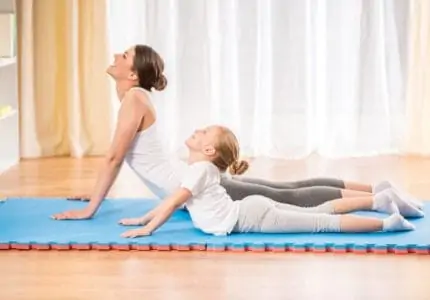 Mother and daughter doing yoga exercises on a mat