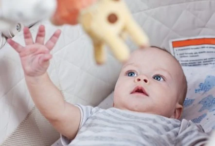 Baby playing with mobile in his crib