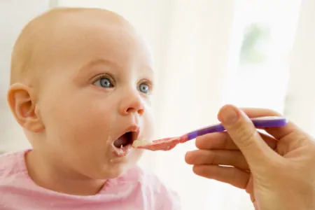 Mother feeding hummus to baby