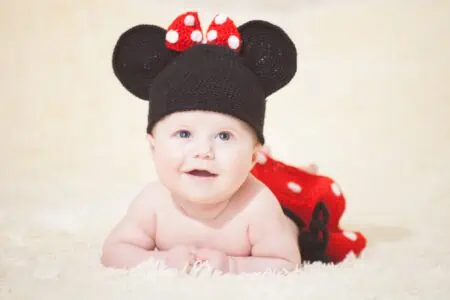 Little boy dressed as Mickey Mouse lying on the bed.