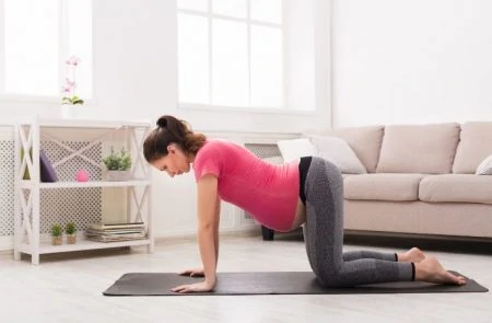 Pregnant woman stretching on yoga mat to induce labor