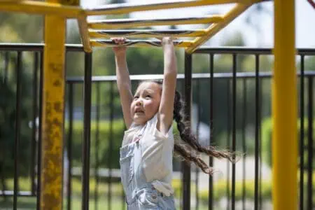 Tough young girl playing on monkey bar