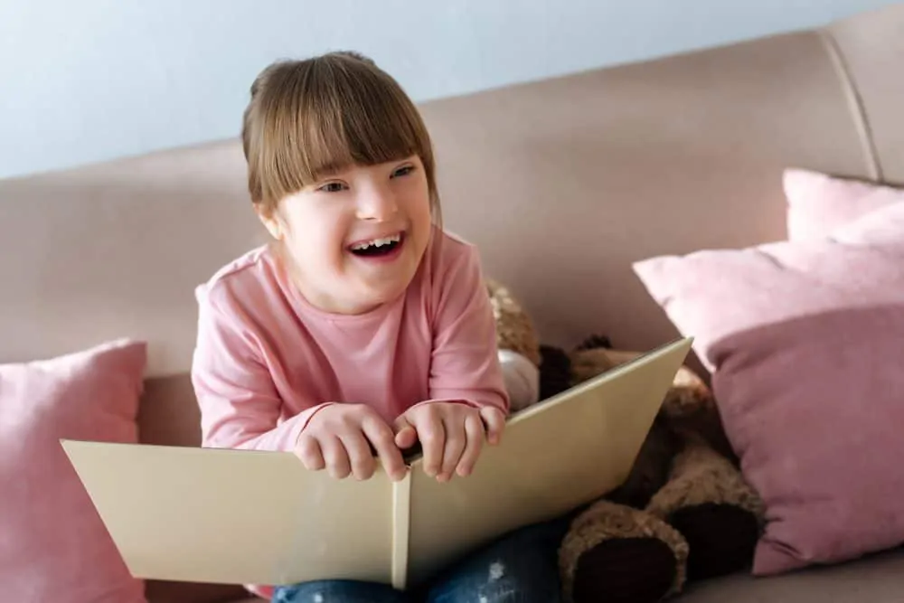 Beautiful little girl laughing while reading a funny poem