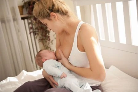 Blonde mother hand expressing milk to her baby