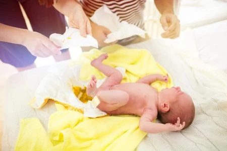 Parents changing dirty diaper of newborn child