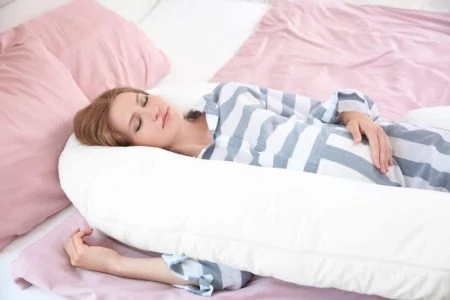 Pregnant woman sleeping with a pregnancy pillow