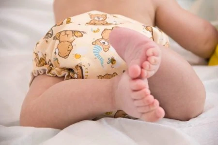 Baby wearing a cloth diaper lying on his stomach