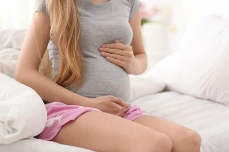 Pregnant woman checking her belly while sitting on the couch