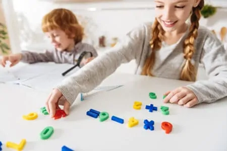 Adorable cheerful siblings solving math riddles together