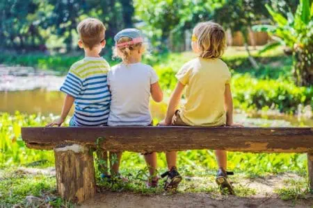 Three children rest during a hike in the woods.