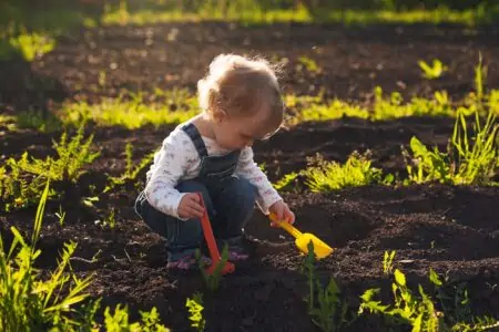 Little boy playing with toy shovels in the garden